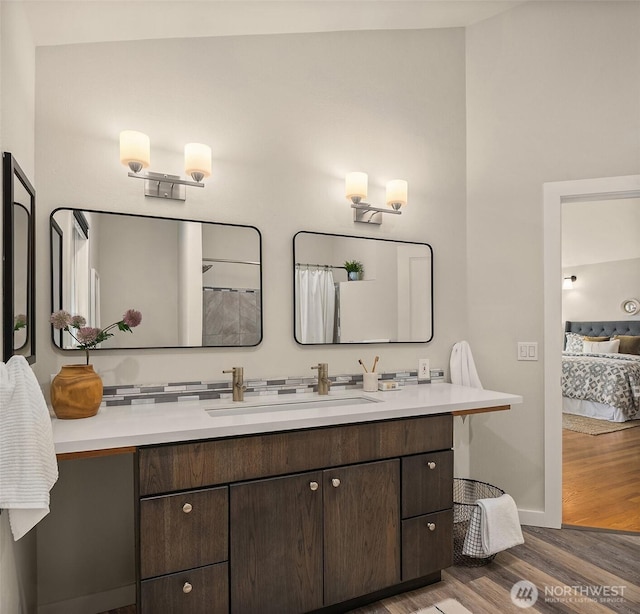 ensuite bathroom featuring connected bathroom, baseboards, wood finished floors, and vanity