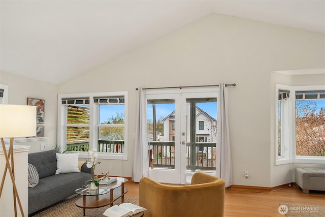 living area with light wood-style flooring, baseboards, and high vaulted ceiling