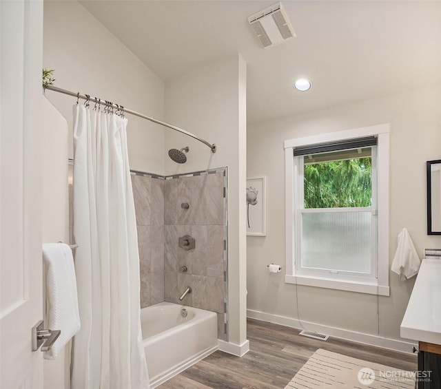 bathroom featuring visible vents, baseboards, wood finished floors, and shower / bath combination with curtain