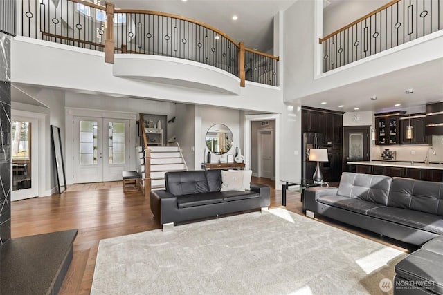 living area featuring stairs, wood finished floors, and french doors