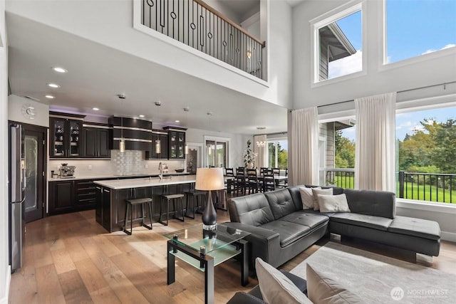 living room featuring recessed lighting, light wood-style flooring, and a towering ceiling