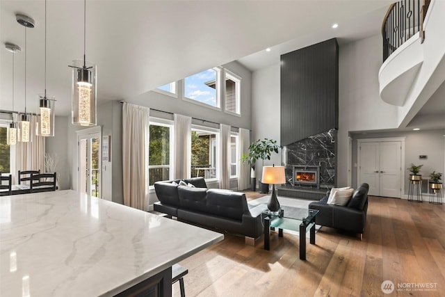 living area featuring recessed lighting, light wood-style flooring, a towering ceiling, and a premium fireplace