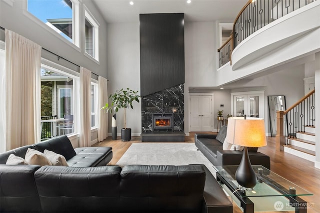 living room with wood finished floors, stairway, french doors, a high ceiling, and a fireplace