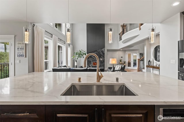 kitchen with open floor plan, dark brown cabinets, and a sink