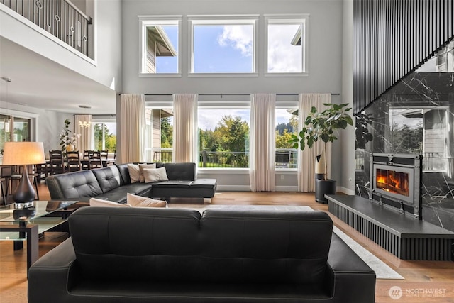 living area with a high ceiling, plenty of natural light, wood finished floors, and a high end fireplace