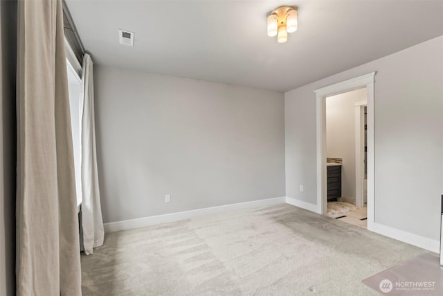 unfurnished bedroom featuring ensuite bath, light colored carpet, visible vents, and baseboards