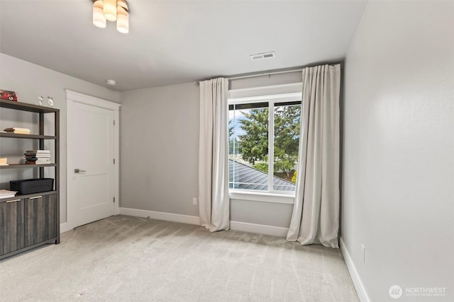 spare room featuring baseboards and light carpet