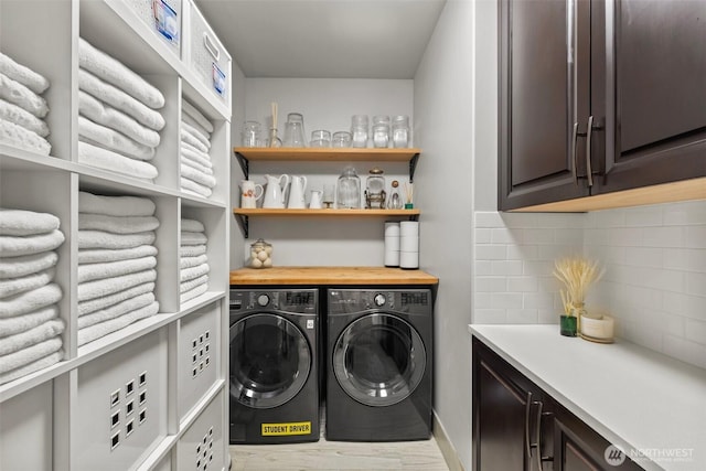 clothes washing area featuring washing machine and dryer and cabinet space