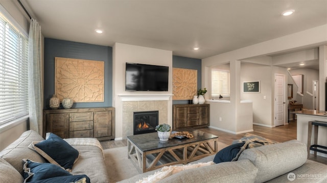 living area with recessed lighting, a tile fireplace, baseboards, and wood finished floors