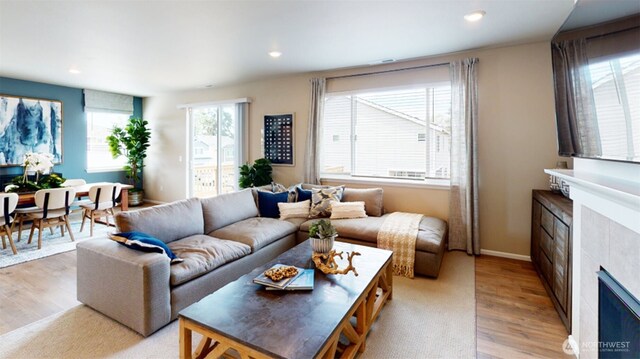 living room featuring recessed lighting, light wood-style floors, baseboards, and a tile fireplace