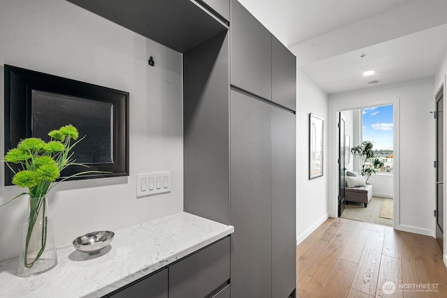 corridor with light wood-style floors and baseboards