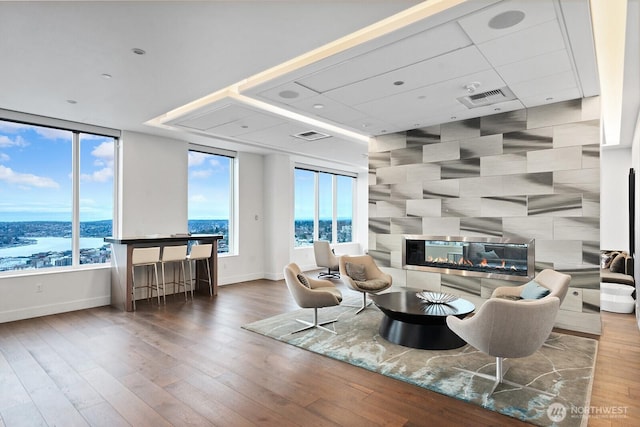 living room featuring visible vents, baseboards, wood finished floors, and a fireplace