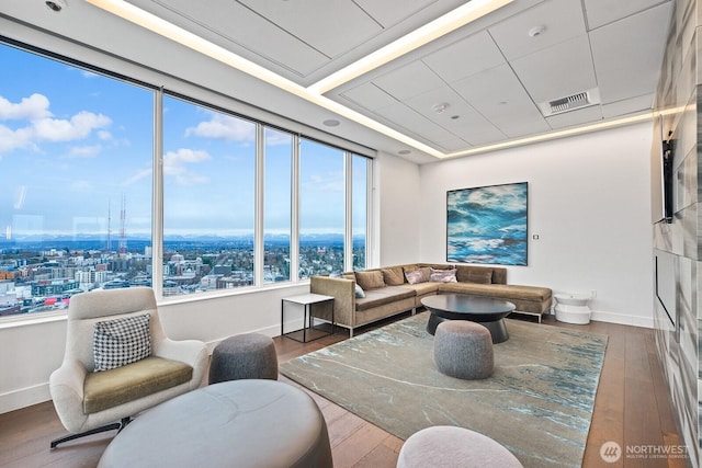 living area with a view of city, baseboards, visible vents, and wood-type flooring