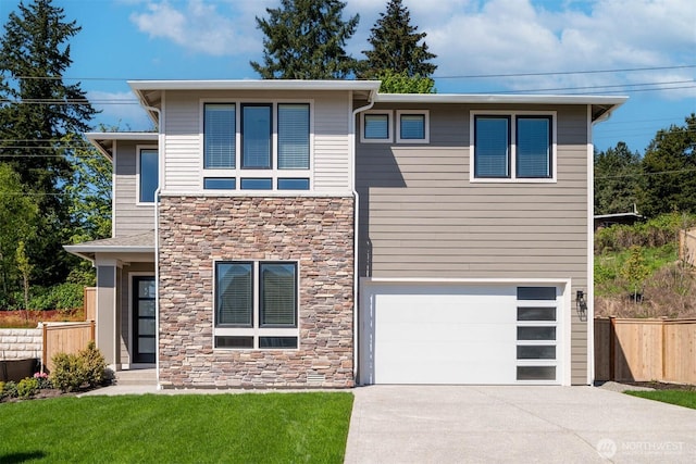 view of front of house featuring a front lawn, fence, concrete driveway, stone siding, and an attached garage