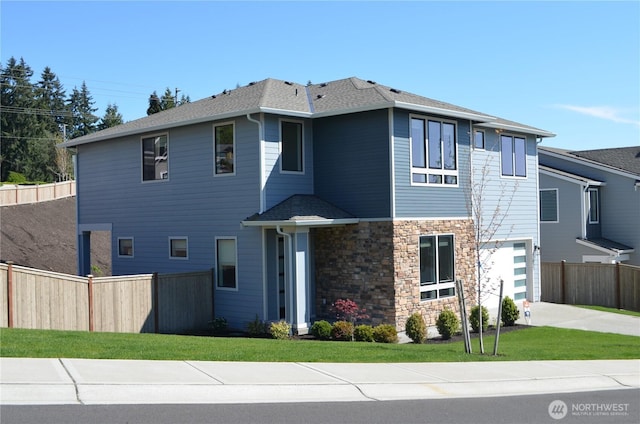 view of front of home featuring fence, a shingled roof, concrete driveway, and stone siding