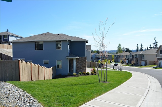 rear view of house featuring a lawn, fence, and a residential view