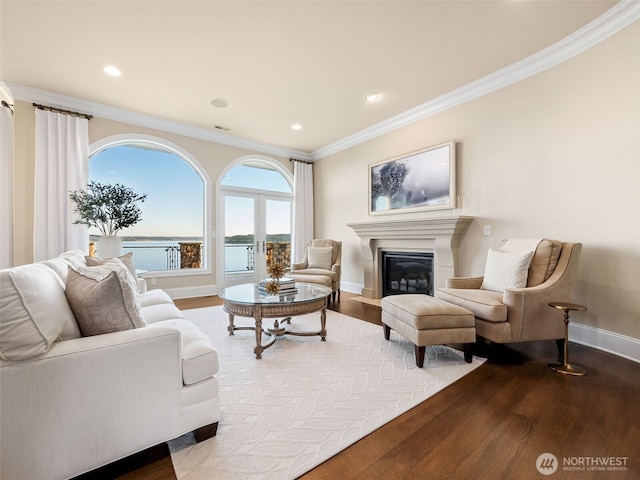 living area with a glass covered fireplace, crown molding, baseboards, and dark wood-style flooring