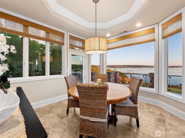 dining area featuring visible vents, baseboards, crown molding, a water view, and a raised ceiling