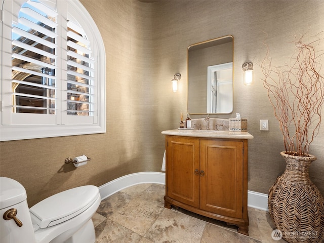 half bath featuring toilet, vanity, and baseboards