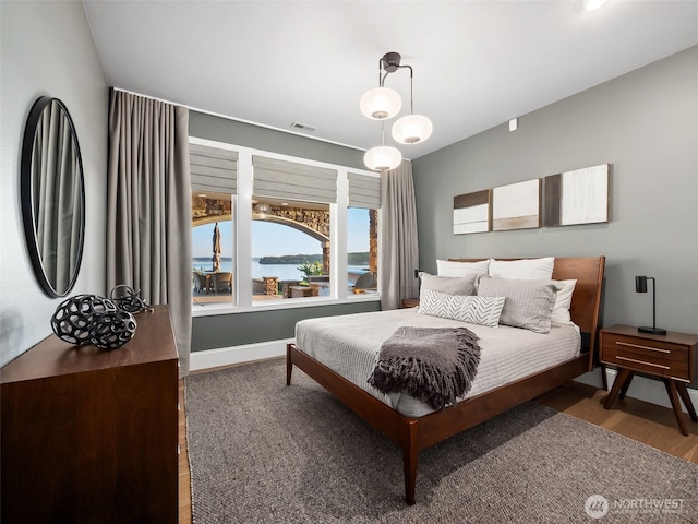 bedroom with visible vents, baseboards, and wood finished floors