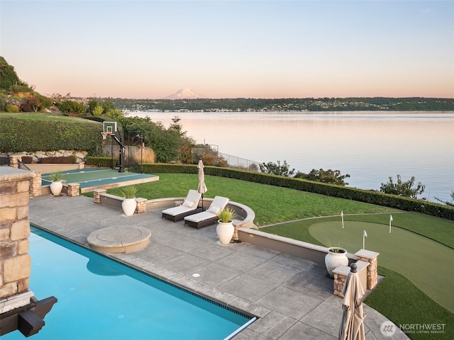 view of swimming pool featuring community basketball court, a yard, and a water view