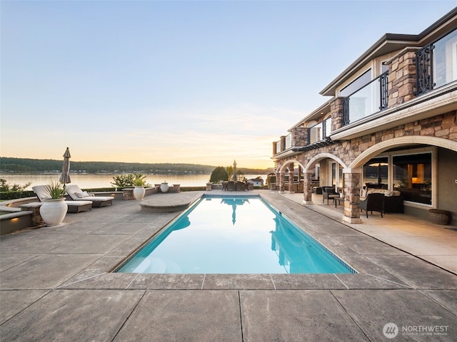 outdoor pool with a patio and a water view