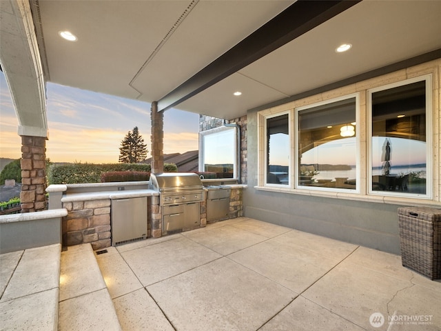 patio terrace at dusk featuring area for grilling and a grill