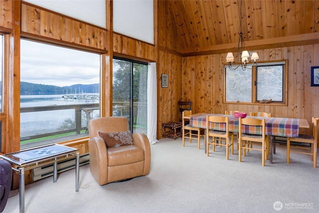 239 Shoreland Dr, Lopez Island, WA 98261 - carpeted dining space with a water view, a chandelier, wood walls, lofted ceiling, and baseboard heating