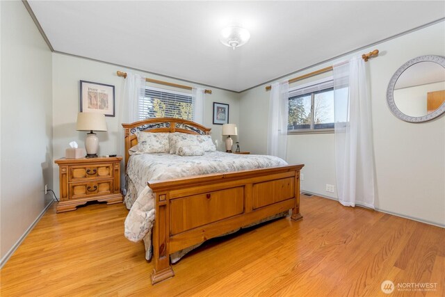 bedroom with light wood-style floors and ornamental molding