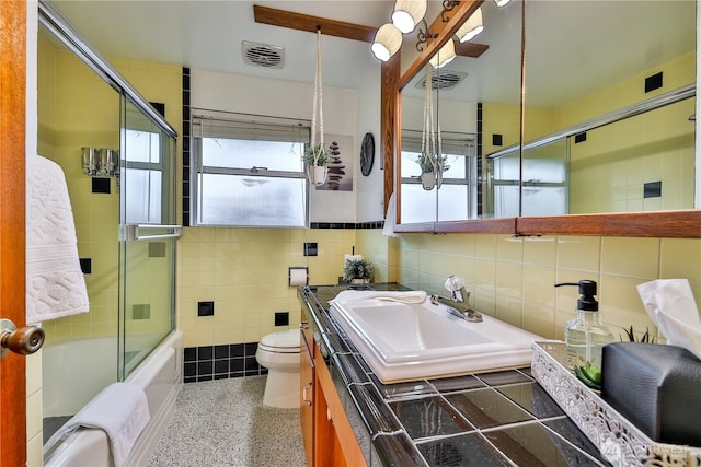 full bathroom featuring vanity, speckled floor, visible vents, tile walls, and toilet