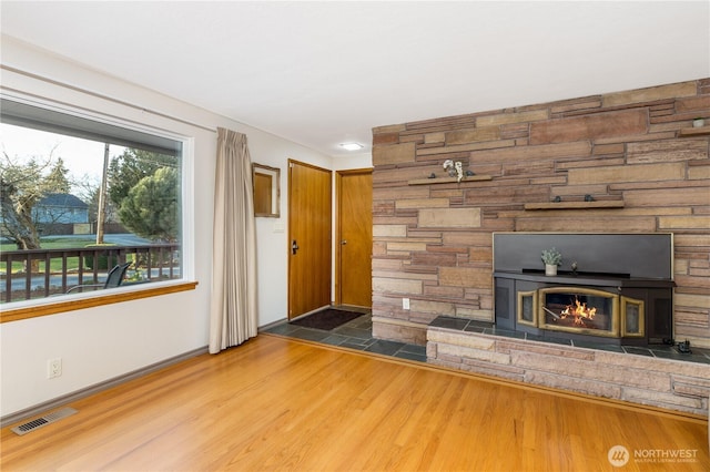 unfurnished living room featuring visible vents, baseboards, and wood finished floors