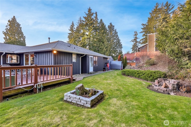 back of property with a wooden deck, a lawn, and board and batten siding