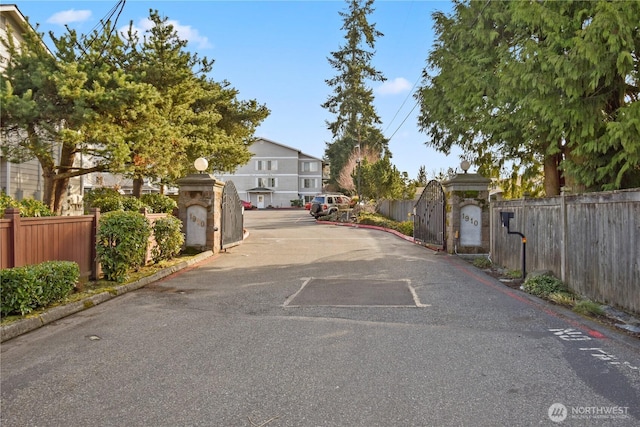 view of street with curbs, a residential view, a gated entry, and a gate