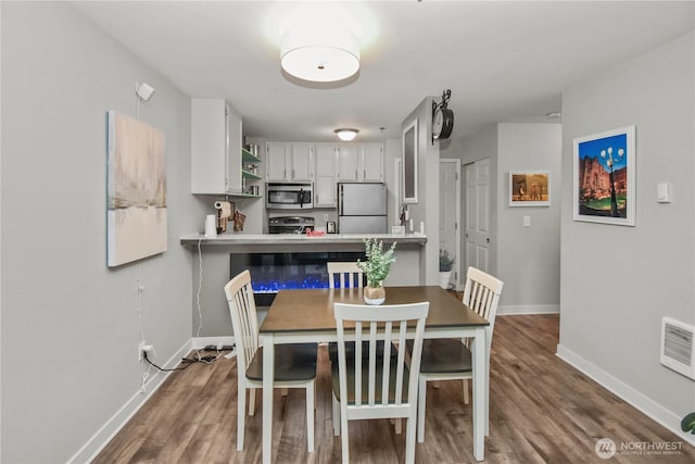 dining room featuring visible vents, baseboards, and wood finished floors