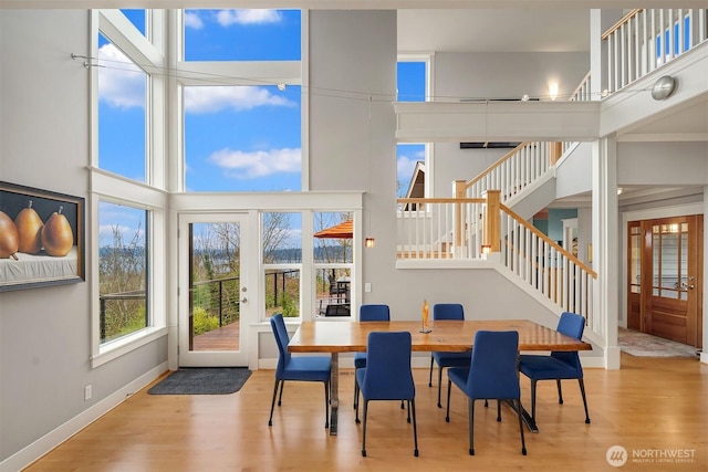 dining area with stairway, a towering ceiling, and wood finished floors