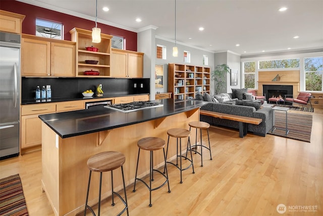 kitchen with dark countertops, light brown cabinetry, a kitchen breakfast bar, light wood-style floors, and stainless steel appliances