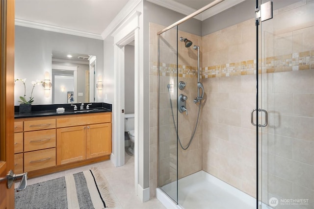 bathroom with crown molding, toilet, a stall shower, tile patterned floors, and vanity