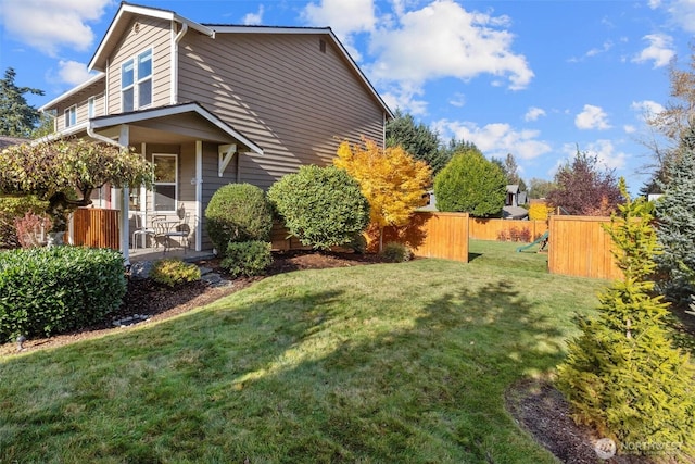 view of side of home with a lawn and fence