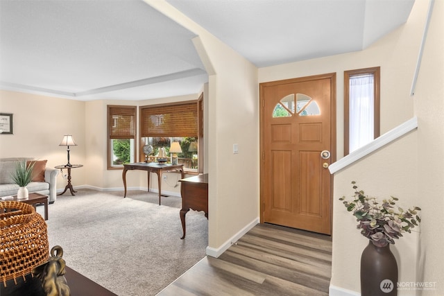 carpeted foyer entrance with baseboards and wood finished floors