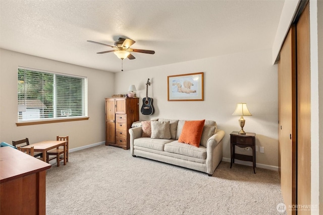 carpeted living area with a textured ceiling, baseboards, and a ceiling fan