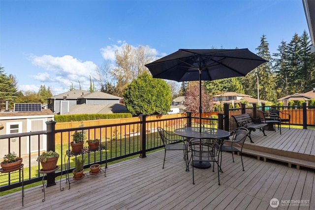 deck featuring a storage unit, an outdoor structure, outdoor dining space, and fence