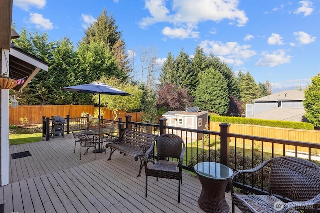 wooden terrace with outdoor dining space, an outdoor structure, a fenced backyard, and a shed