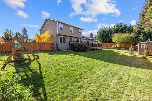 rear view of property featuring a fenced backyard, an outdoor structure, a storage unit, a playground, and a lawn