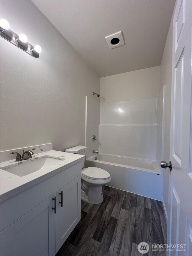 full bath featuring tub / shower combination, toilet, wood finished floors, and vanity