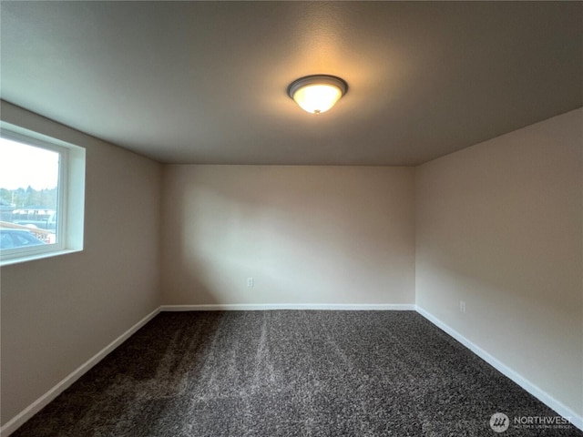 unfurnished room with dark colored carpet and baseboards