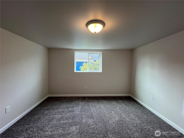 unfurnished room featuring dark colored carpet and baseboards