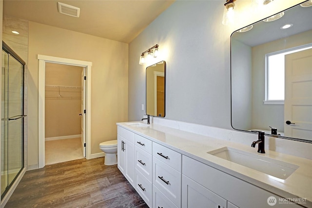 full bathroom featuring a stall shower, wood finished floors, visible vents, and a sink