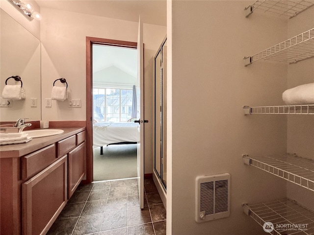 ensuite bathroom featuring connected bathroom, heating unit, a stall shower, and vanity