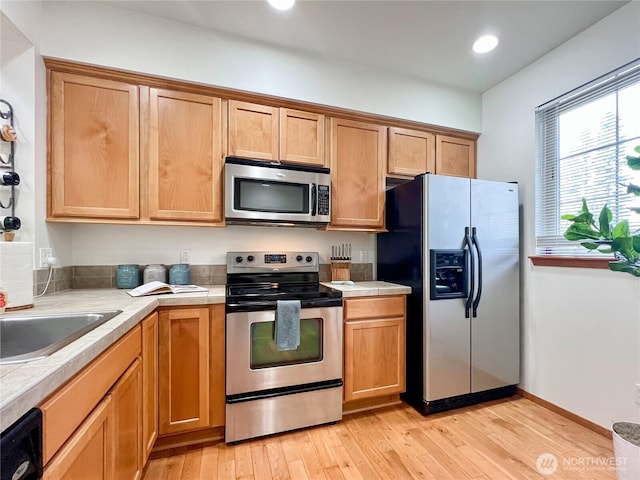 kitchen with recessed lighting, stainless steel appliances, light wood-style floors, baseboards, and tile counters