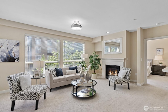 carpeted living room with a glass covered fireplace and baseboards